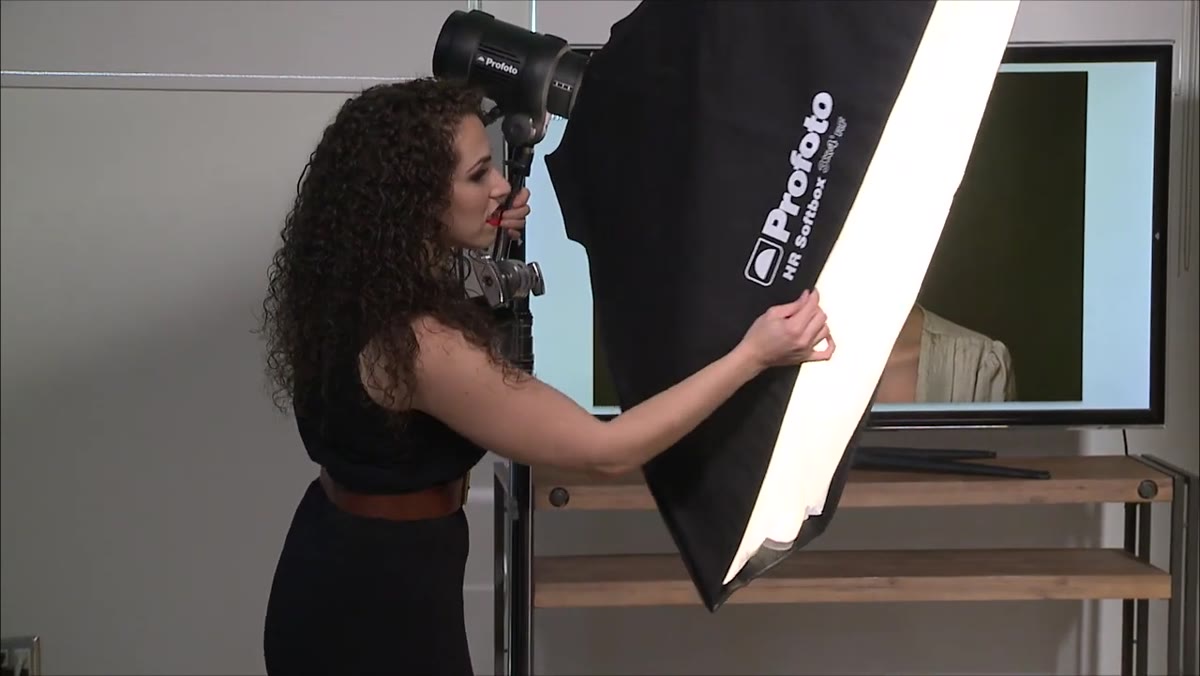 Photographer positioning light; subject blending into black background